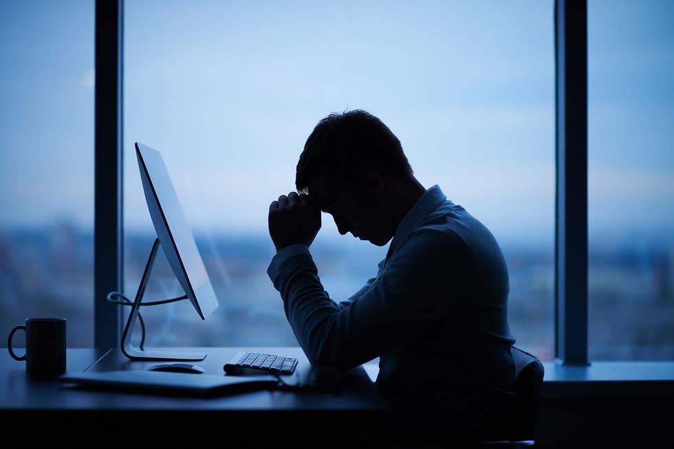 Someone sitting alone at a desk in low light